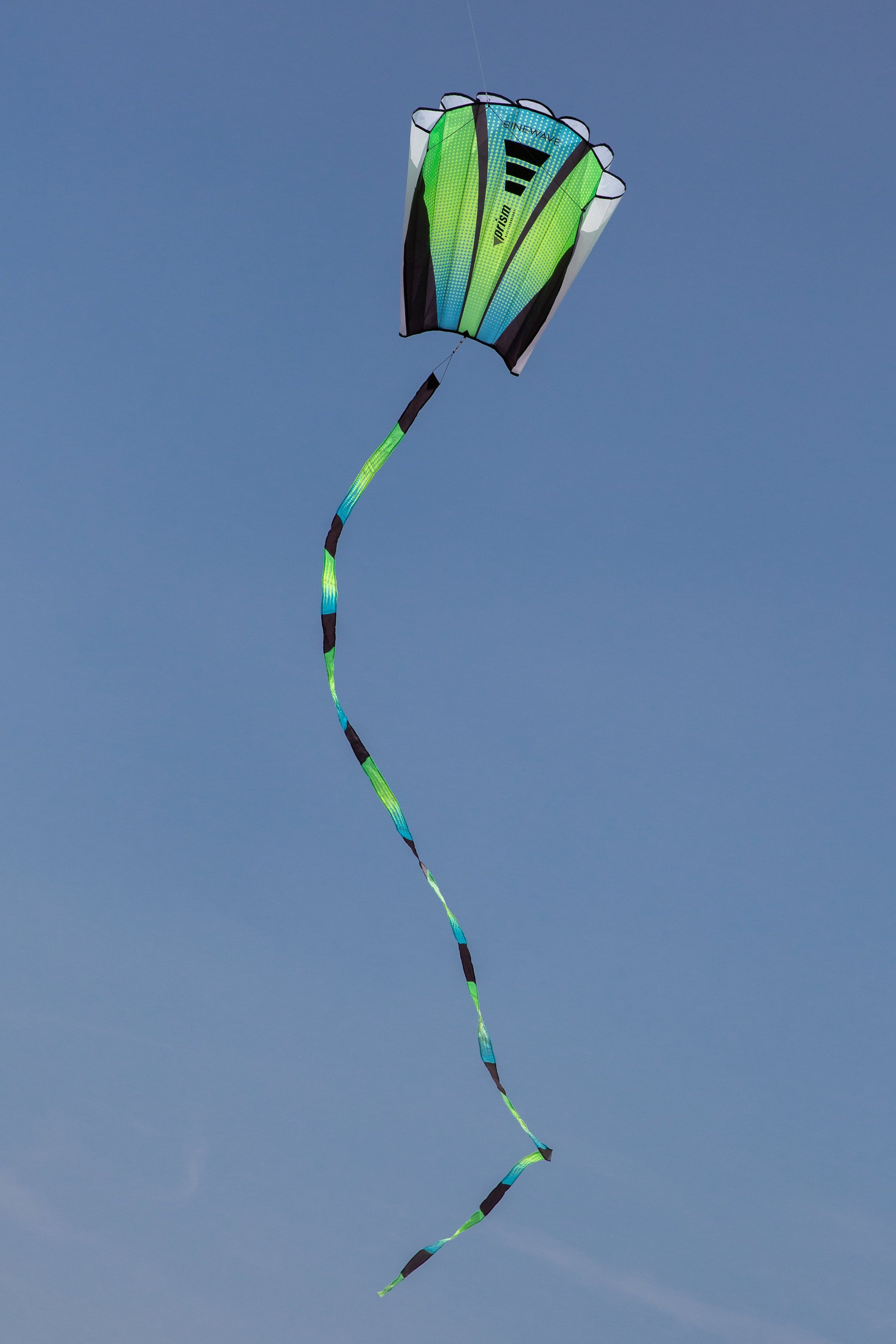 The Aurora Sinewave (blue, yellow and green) in flight with a cloudless blue sky in the background.