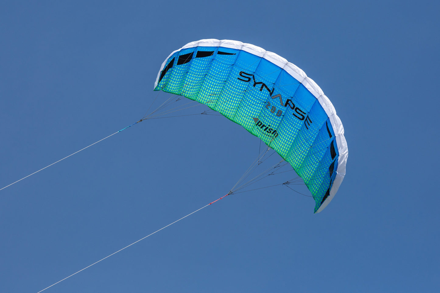 A blue/green Synapse 200 flying against a cloudless blue sky