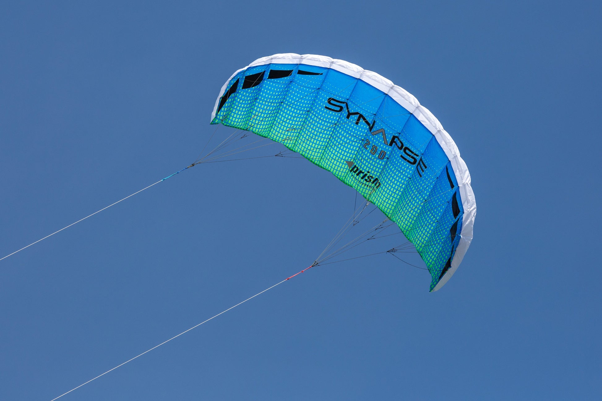 A blue/green Synapse 200 flying against a cloudless blue sky