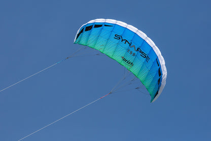 A blue/green Synapse 200 flying against a cloudless blue sky